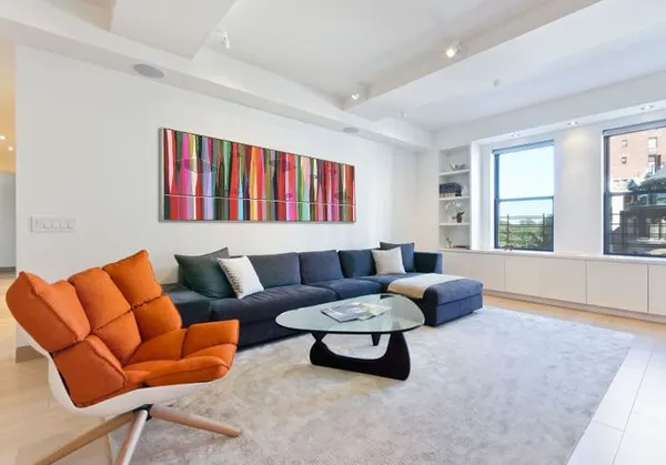 дизайн белой гостиной с оранжевым креслом в интерьере