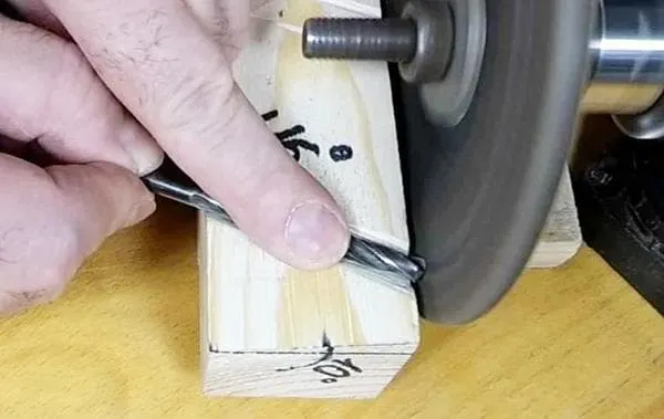 заточка сверла на точильном круге с упором на деревянный брусок 